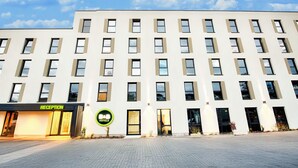 A modern hotel building with a reception area, multiple floors, and a clear sky. - B&B Hotel Kempten (Kempten)