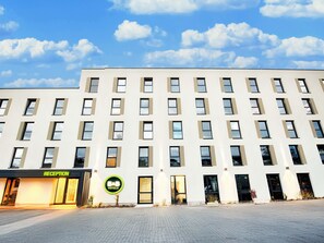 A modern hotel building with a reception area, multiple floors, and a clear sky. - B&B Hotel Kempten (Kempten)