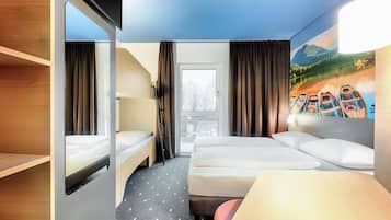 Een hotelkamer met een stapelbed, een bureau en een groot raam.