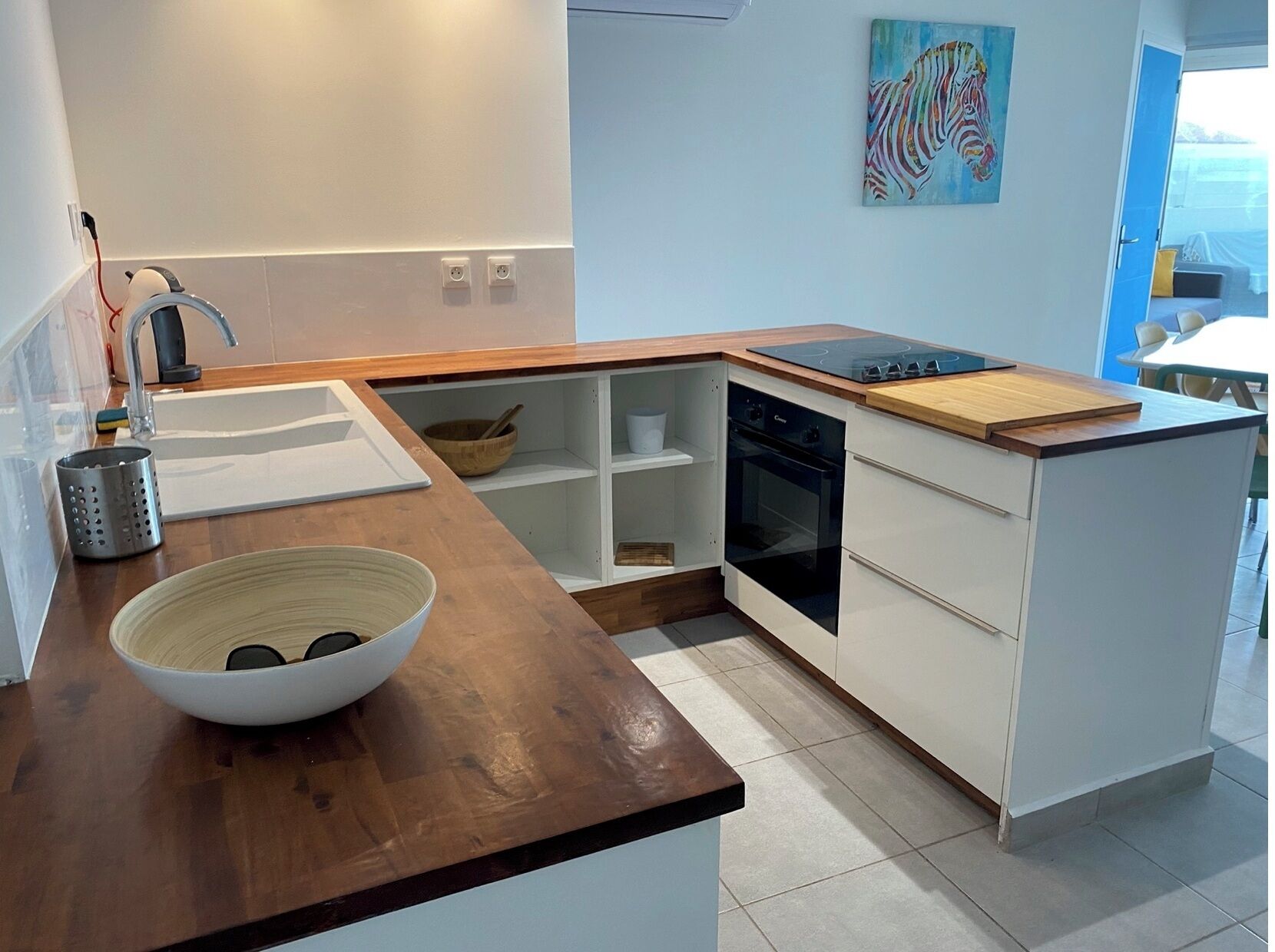 Una cucina moderna con un piano di lavoro in legno, forno integrato e una ciotola sul bancone.