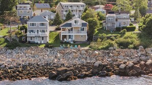 Une zone résidentielle côtière, avec des maisons, un littoral rocheux et une vue dégagée sur la mer.
