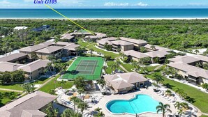 A residential complex with multiple buildings, a tennis court, and a swimming pool.