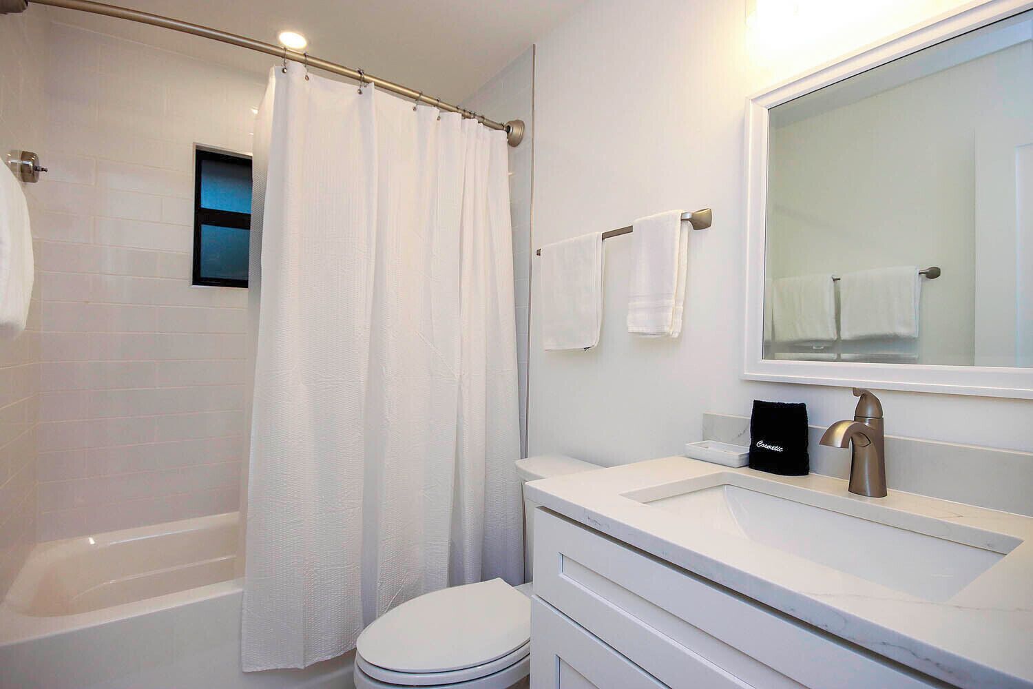 A modern bathroom with a bathtub, toilet, and vanity with a mirror.