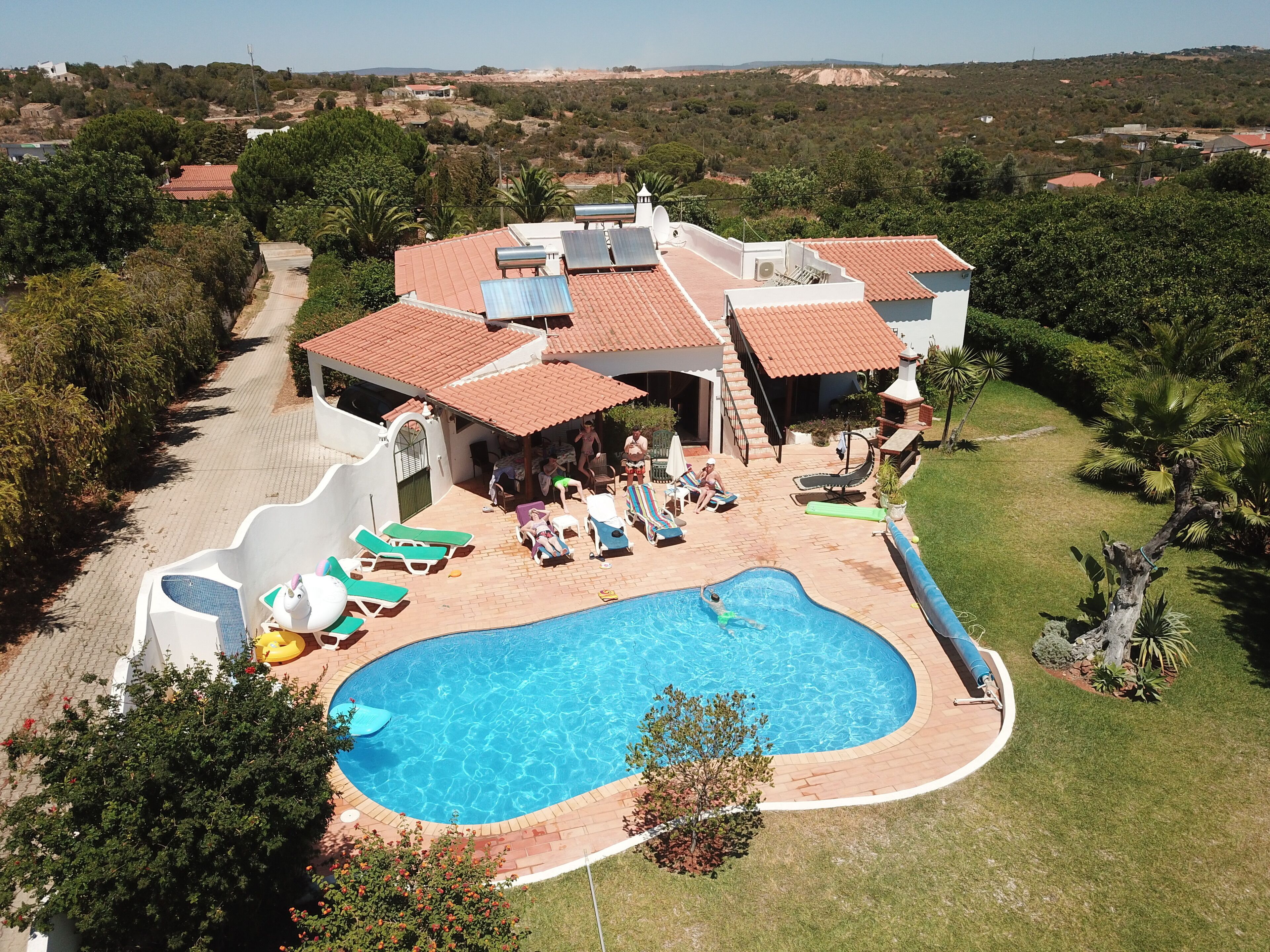 A large house with a swimming pool, a slide, and a patio area with sun loungers.