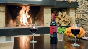 A fireplace with a fire, a bottle of wine, and two glasses of wine on a table. - Extreme (Smolyan)