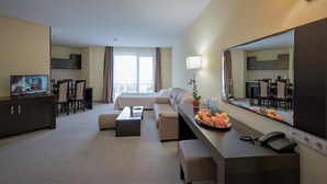 A hotel room with a sofa, a dining table, a TV, a mirror, and a fruit bowl. - Extreme (Smolyan)