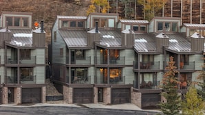 A multi-story residential building with a modern architectural design, featuring balconies, large windows, and a garage entrance.