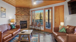 A cozy living room with a fireplace, leather sofas, and a stone accent wall.