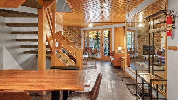 A wooden staircase leading to a dining area with a fireplace and seating.