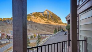 A mountain view from a balcony with a railing, a road in the foreground, and buildings in the background.