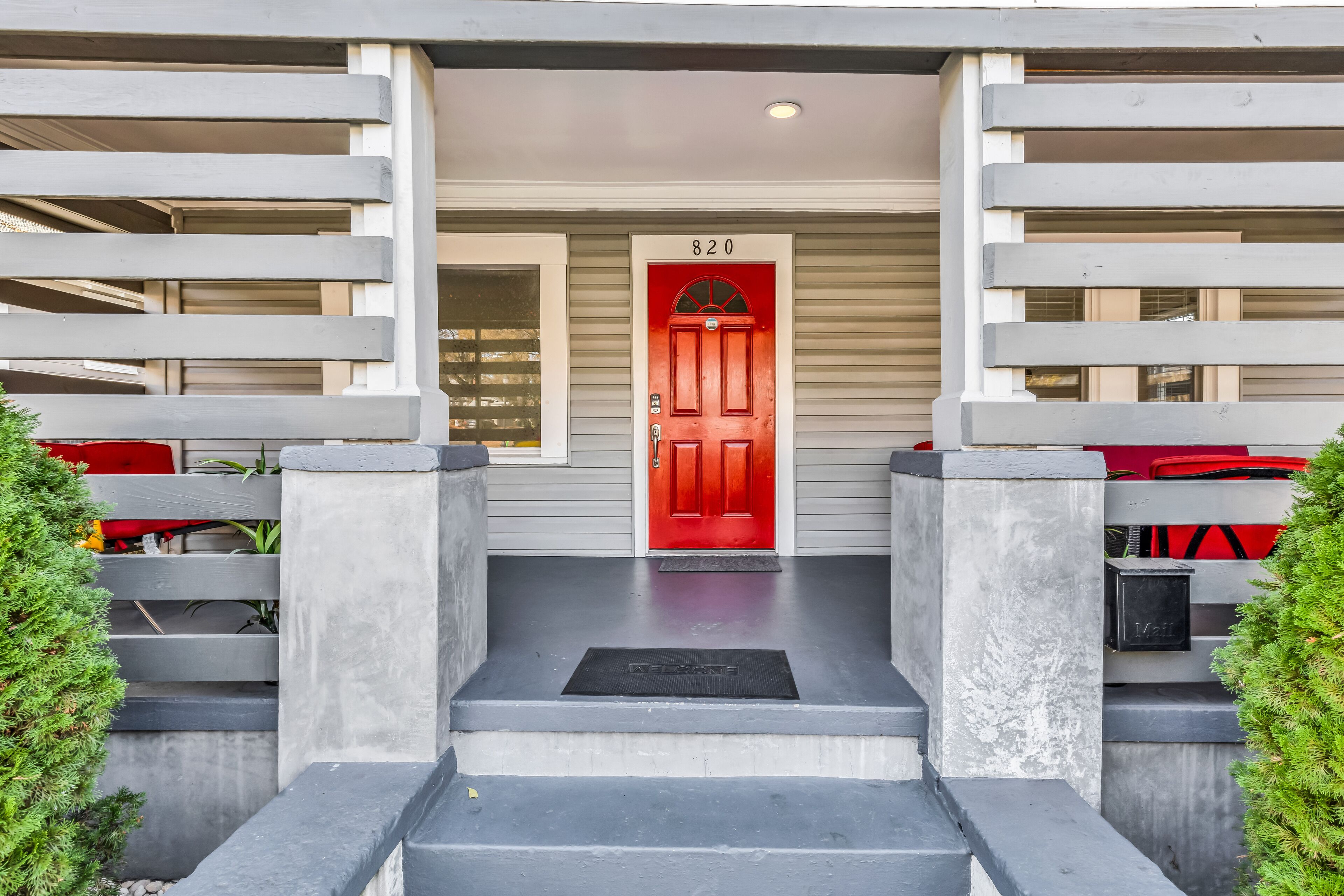 A red door with the number 820, a concrete staircase, and a metal mailbox.
