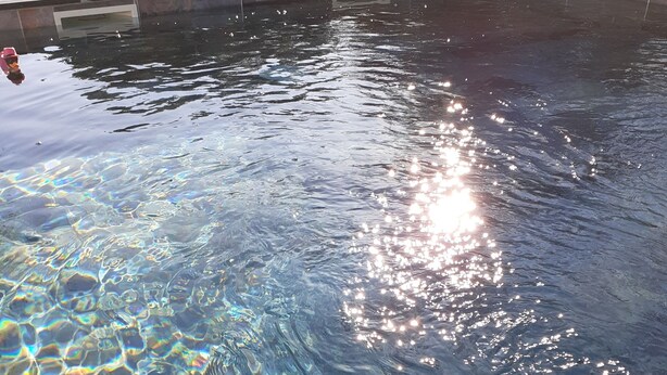 Ein klares Schwimmbecken mit sichtbaren Wellen und Spiegelungen.