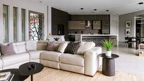 Een moderne woonkamer met een beige bank, een bijzettafeltje en een potplant.