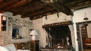 Una habitación rústica con paredes de piedra vista, chimenea, sofá y candelabro.