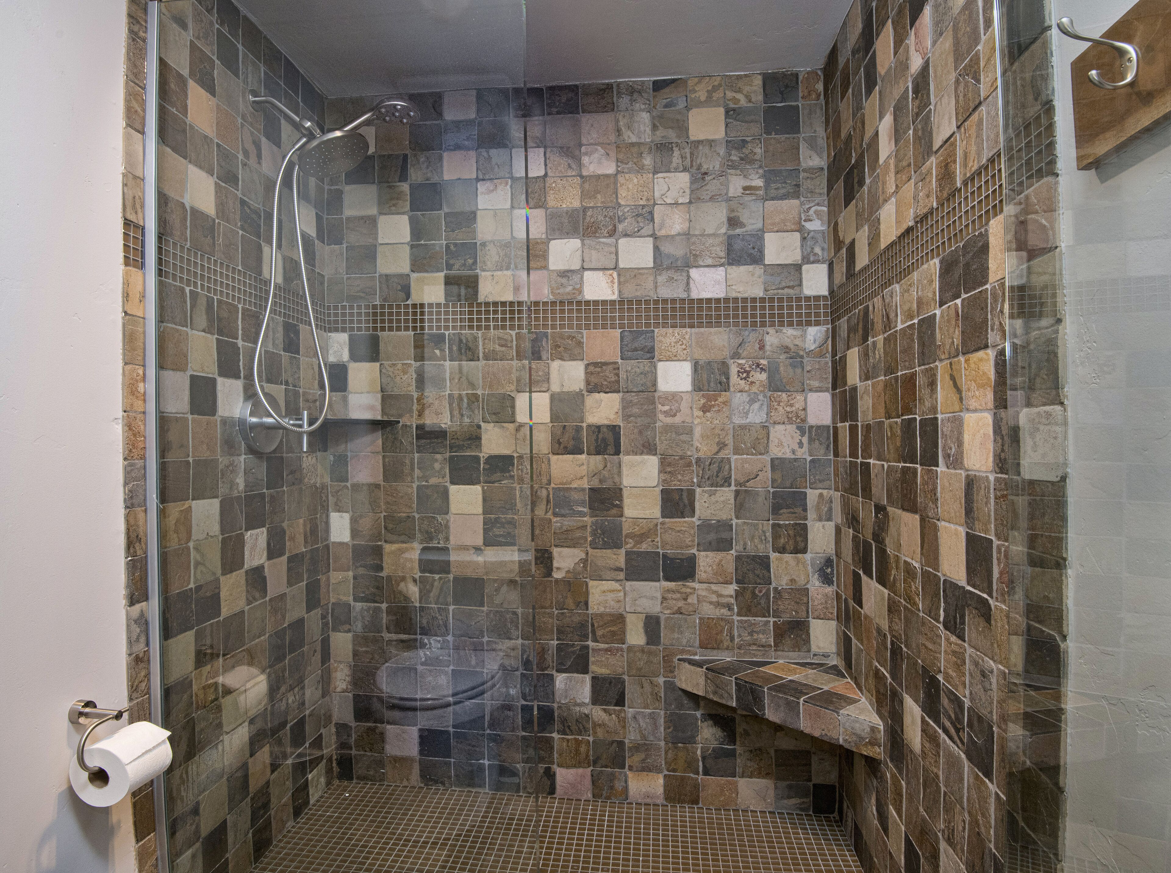 A shower area with a tiled wall and a glass door.