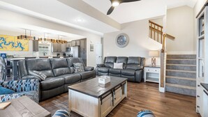 A spacious living room with a large sofa, a coffee table, and a dining area in the background. - Enjoy New Arcades & Outdoor Slide, Private Hot Tub, Close to SDC, Free Tickets & Pickleball (Hollister)