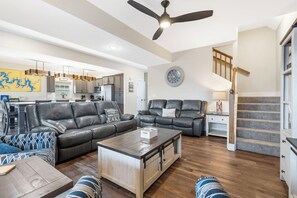 A spacious living room with a large sofa, a coffee table, and a dining area in the background. - Enjoy New Arcades & Outdoor Slide, Private Hot Tub, Close to SDC, Free Tickets & Pickleball (Hollister)