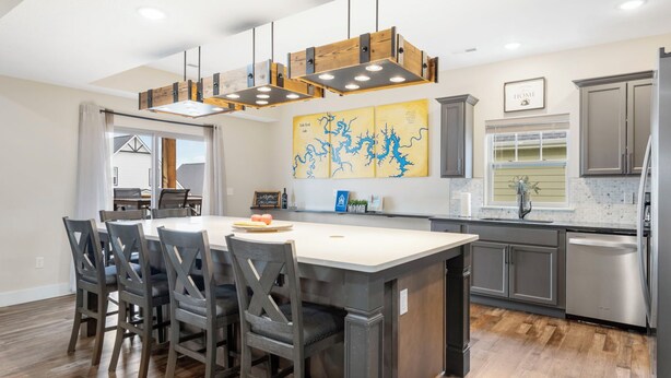 A modern kitchen with a large island, dark wooden chairs, and a hanging light fixture. - Enjoy New Arcades & Outdoor Slide, Private Hot Tub, Close to SDC, Free Tickets & Pickleball (Hollister)