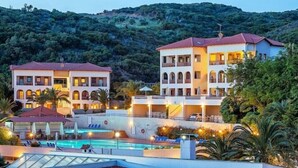 A hotel with multiple buildings, a swimming pool, and lush greenery in the background. - Xenios Theoxenia Hotel (Aristotelis)
