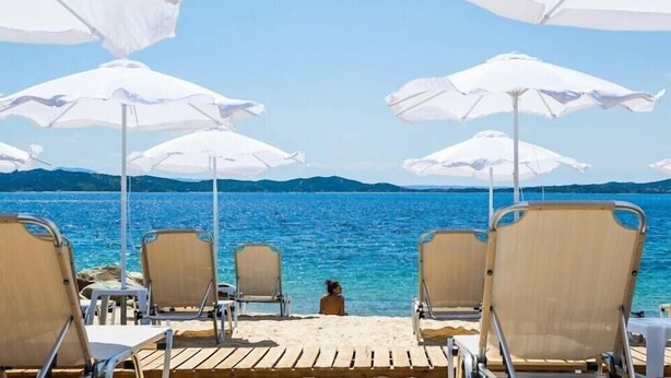 A beach with white umbrellas and chairs facing the sea. - Xenios Theoxenia Hotel (Aristotelis)