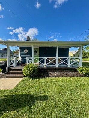 A two-story building with a porch, a green door, and a sign that reads 'Cottage Inn.' - Cozy Cottage: A Memory Making Place by Cedar Point (Huron)