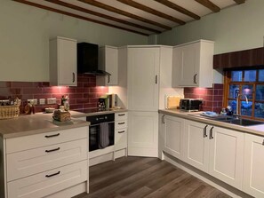 A kitchen with white cabinets, a built-in oven, and a window with a view. - Apartment One, The Carriage House. (York)