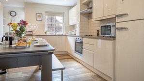Une cuisine moderne avec des meubles blancs, un four en acier inoxydable, un micro-ondes et un réfrigérateur de la marque « SMEG ».