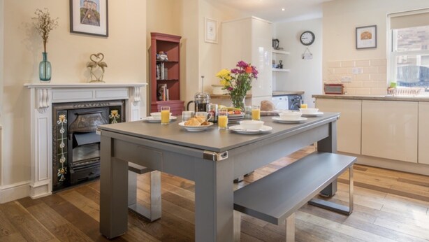 Une cuisine moderne avec une table à manger dressée pour le petit-déjeuner, une cheminée et un îlot central.