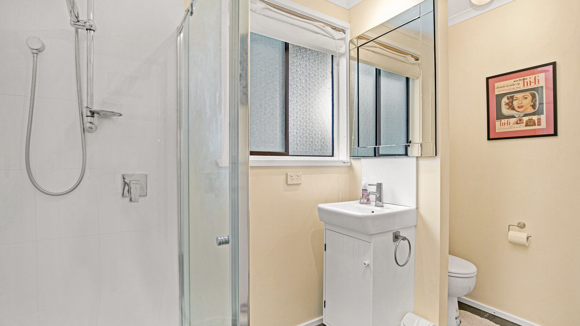 A bathroom with a glass shower enclosure, a white sink, and a toilet.