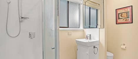 A bathroom with a glass shower enclosure, a white sink, and a toilet.