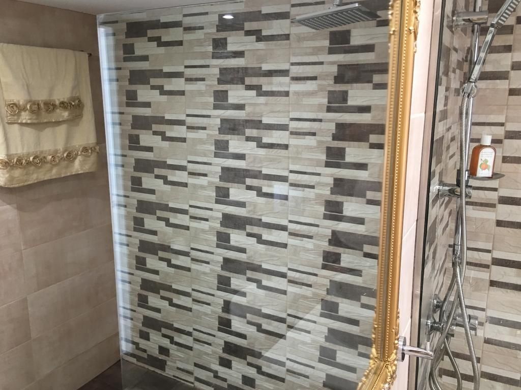Un baño con zona de ducha, una toalla colgada en la pared y una botella de champú en el suelo.