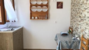 Eine kleine Küche mit einem Holzkorpus, einer Spüle und einem Essbereich mit Tisch und Stühlen.