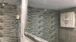 Eine Dusche mit Glasabtrennung und gefliesten Wänden.
