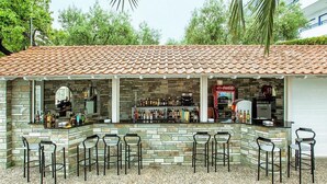 An outdoor bar area with stone walls, a tiled roof, and multiple bar stools. - Xenios Port Marina (Kassandra)