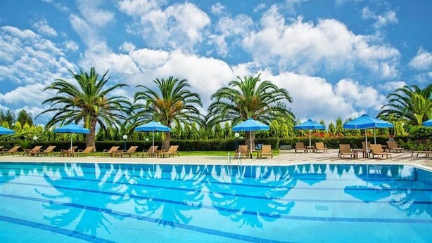 A swimming pool with clear blue water, surrounded by palm trees and lounge chairs. - Xenios Port Marina (Kassandra)