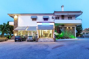 Un hotel de dos plantas con recepción, un balcón y fachada de piedra.