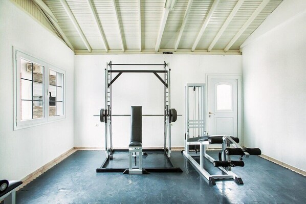 A gym with a squat rack, bench press, and weight plates. - Xenios Port Marina (Kassandra)