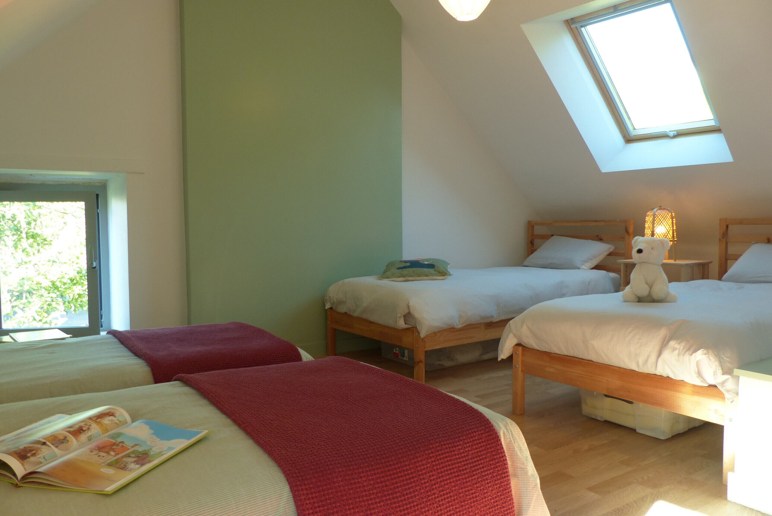 Een kamer met twee bedden, een dakvenster en een raam.