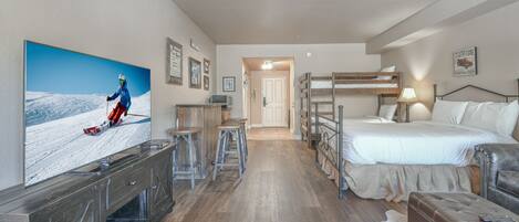 A hotel room with a large TV, bunk beds, a desk, and a cowhide rug.
