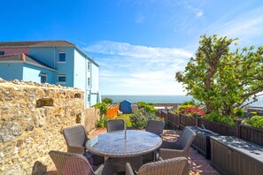 A patio with wicker furniture and a view of the sea. - Jan Dee Cottage (Ventnor)