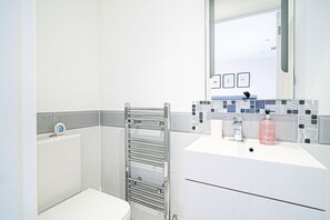 A bathroom with a white sink, a mirror, and a towel rack. - Jan Dee Cottage (Ventnor)