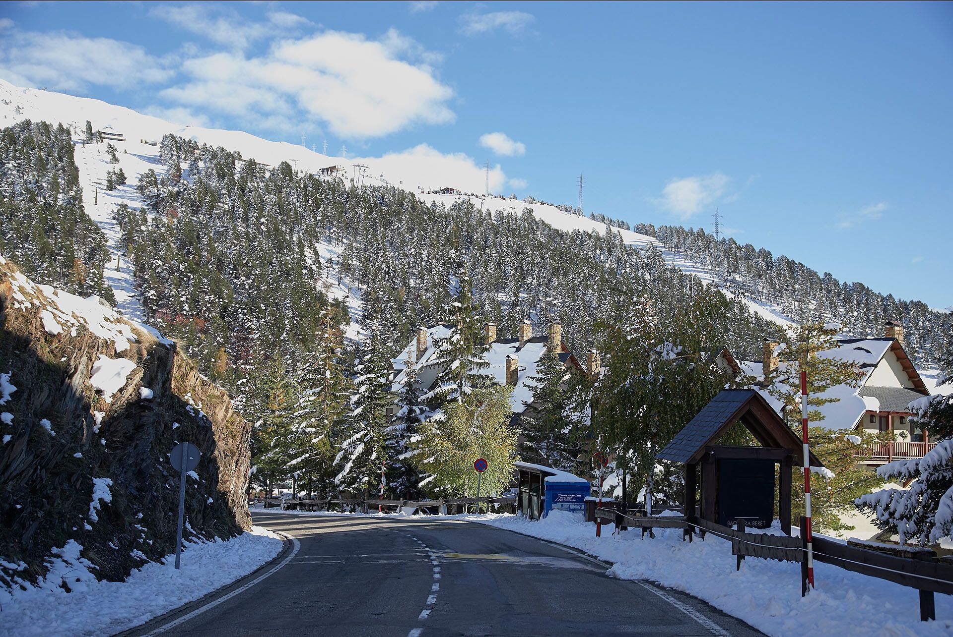 A snow-covered mountain road with a small wooden building on the right.