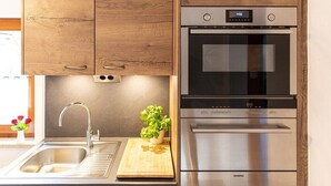 A kitchen with wooden cabinets, a stainless steel sink, a potted plant, and a Siemens oven. - Alm Appartement für 2 Personen (Berchtesgaden)