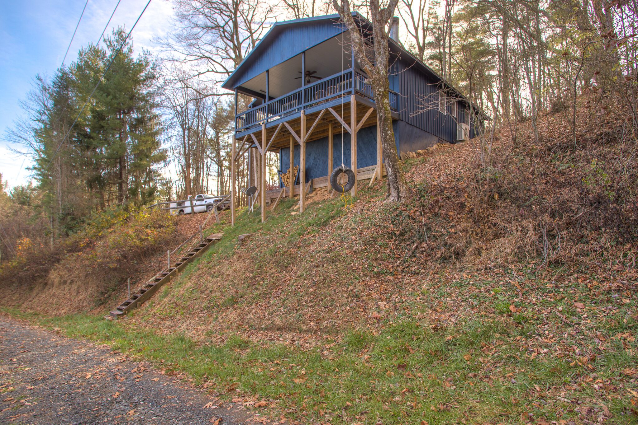 Une cabane dotée d’un balcon, d’un escalier et offrant une vue sur la forêt environnante.