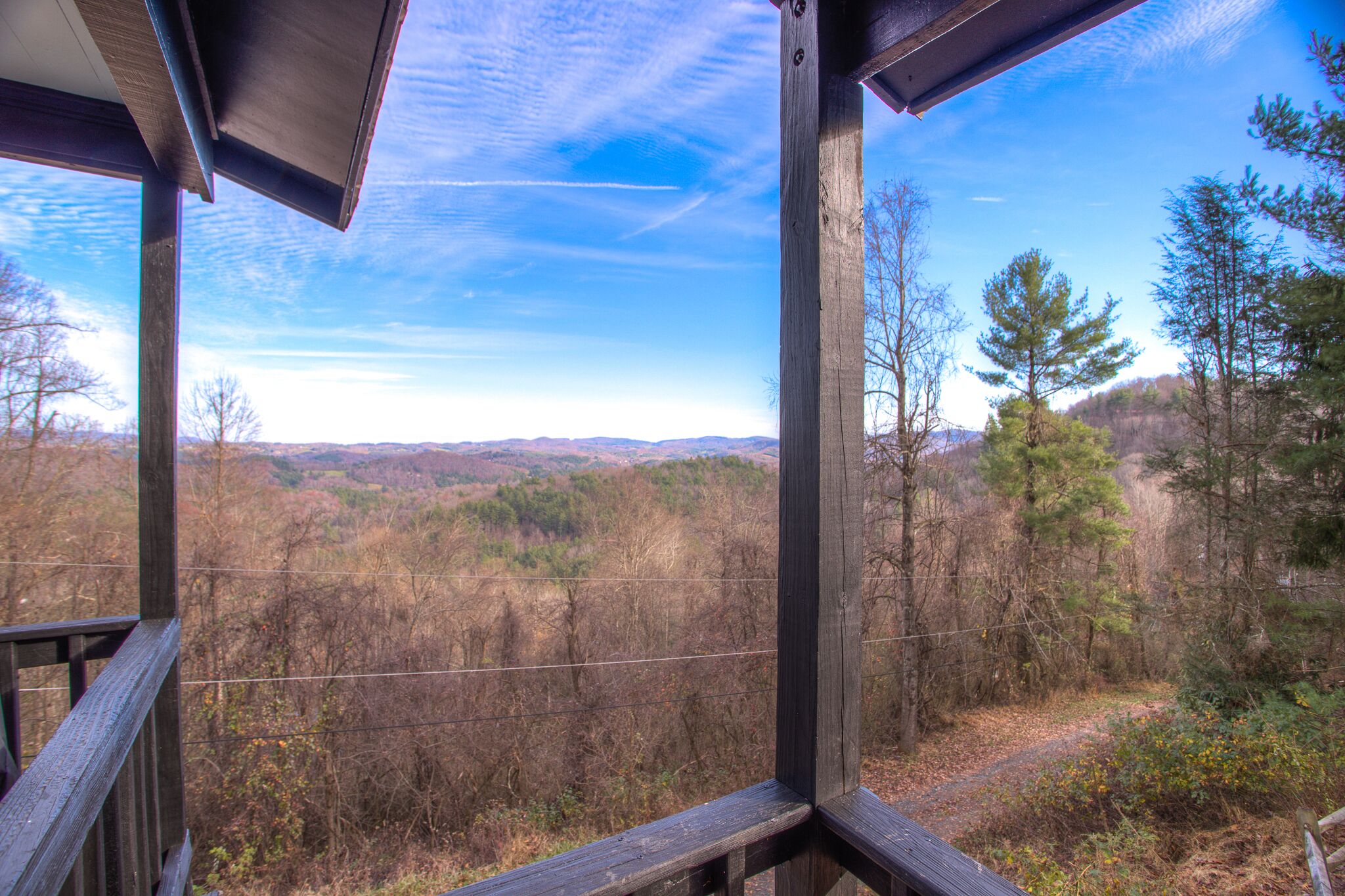 A wooden deck overlooking a forested landscape with a clear sky.