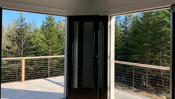 A modern room with large sliding glass doors leading to a balcony with a wooden deck and metal railing.