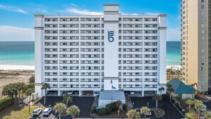 A multi-story hotel with a prominent '5' logo, a parking lot, and a view of the beach. - "Breakers East 304" Gulf Front 2BR/2BA Beach setup included (Destin)