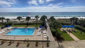 A swimming pool with lounge chairs and umbrellas, a beach with umbrellas and people, and a flag. - "Breakers East 304" Gulf Front 2BR/2BA Beach setup included (Destin)