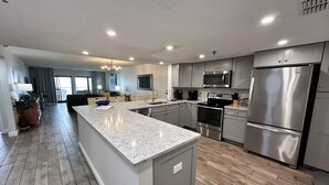 A modern kitchen with granite countertops, stainless steel appliances, and a central island. - "Breakers East 502" Gulf Front 2BR/2BA Beach setup included (Destin)