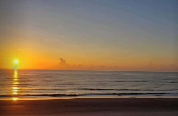 Una spiaggia con il tramonto sull'oceano.
